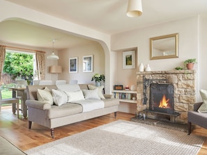 A living room with a stone fireplace, a sofa with cushions, a coffee table, and a bookshelf.