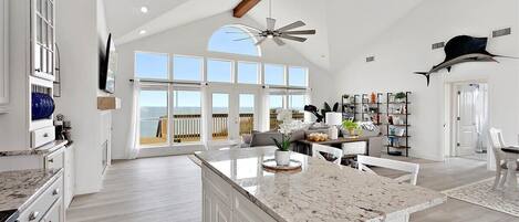 A spacious kitchen with a large island, white cabinetry, and a ceiling fan.