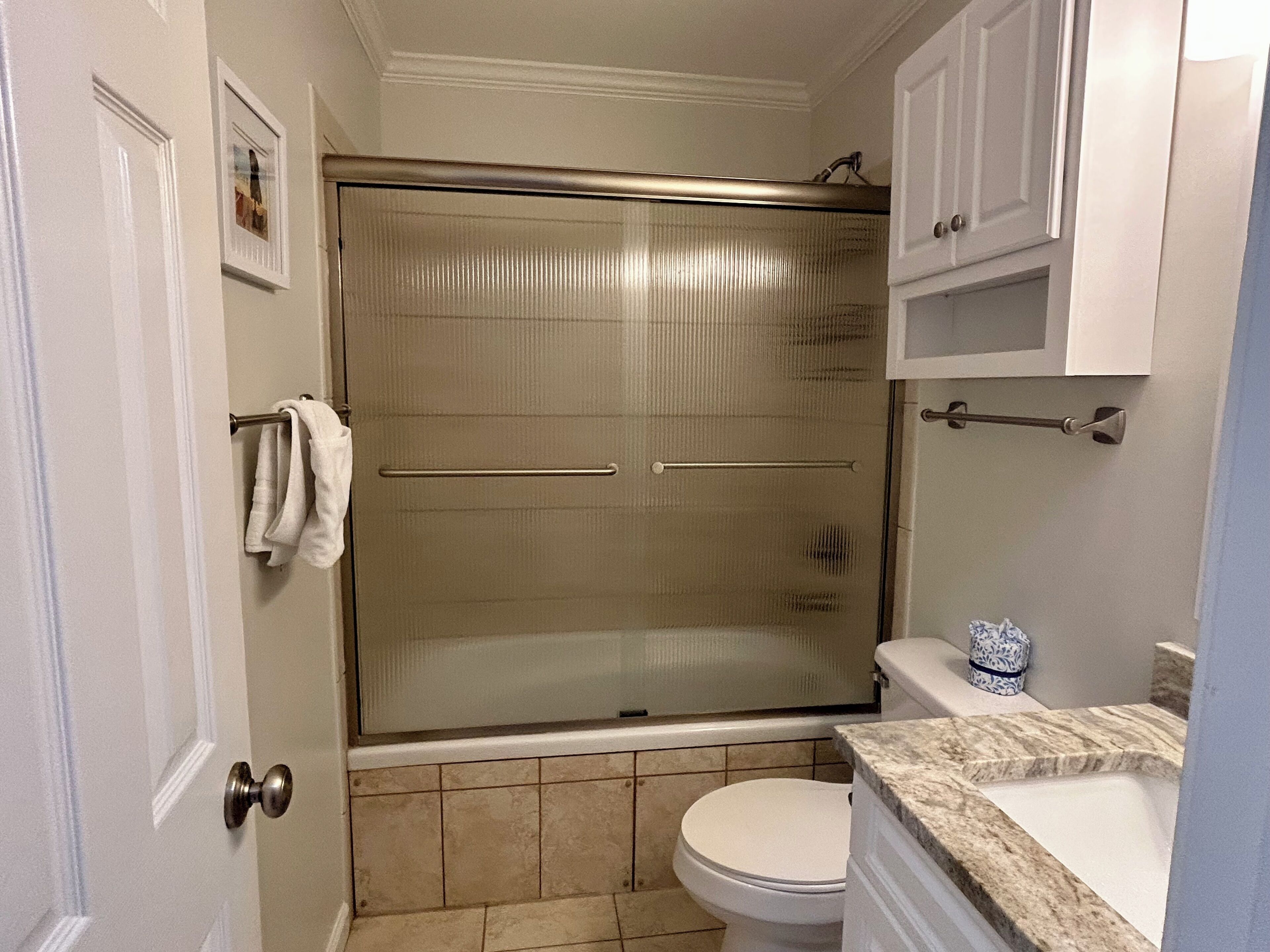 Une salle de bain dotée d’une douche à parois de verre, de toilettes et d’un lavabo avec un plan de travail en marbre.