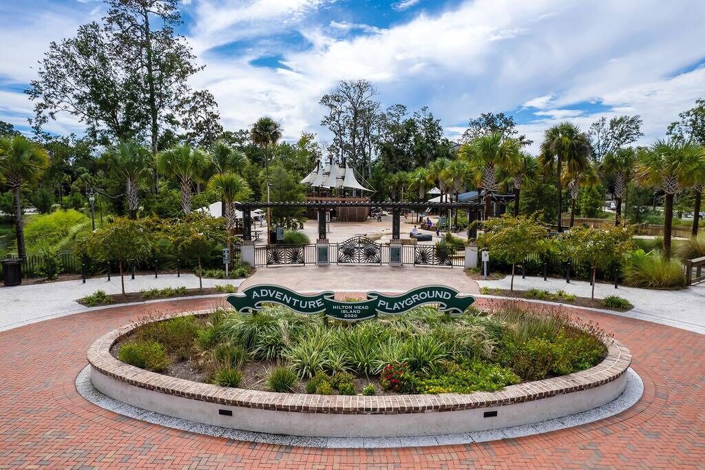 A circular brick pathway leading to a gazebo with a sign reading "Adventure Playground."