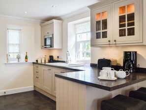A kitchen with white cabinets, a microwave, a coffee maker, and a window with a view.