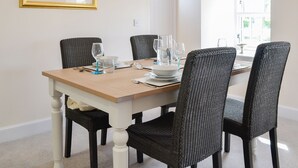 A dining table with four chairs, a framed painting, and a window with blinds. - Grieve's Cottage - UK11107 (Montrose)