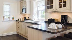 Una cocina con armarios blancos, microondas, cafetera y ventana con vistas.