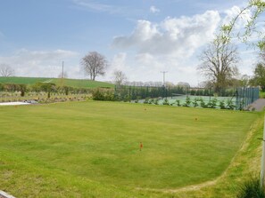 A golf course with a clear sky, green grass, and trees.