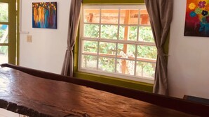 Une pièce avec un banc en bois, une fenêtre avec des rideaux et deux tableaux accrochés au mur.