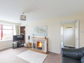 A living room with a fireplace, a television, a sofa, and a bookshelf. - 2 bedroom accommodation in Brahan, near Dingwall (Brahan, near Dingwall)