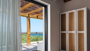 Une chambre avec vue sur la mer, une pergola en bois et une porte coulissante dotée de panneaux tressés.