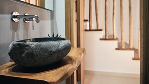 Un évier en pierre avec un robinet moderne, installé sur un plan de travail en bois.
