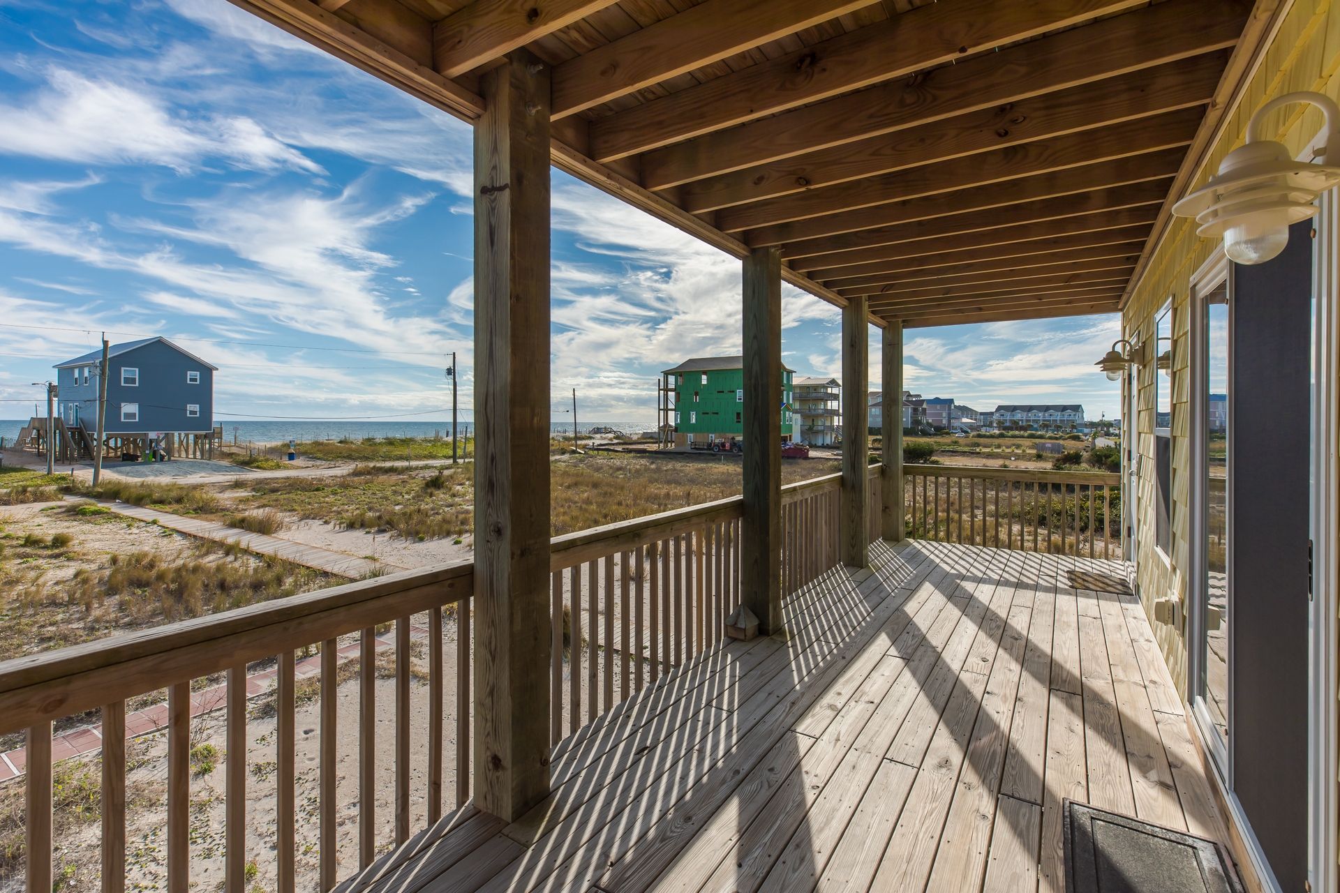 A wooden deck with a view of the beach and houses.