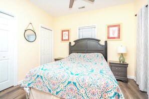 A bedroom with a bed, a nightstand, a lamp, a mirror, and a door.