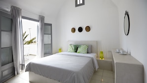 A modern bedroom with a large bed, a bedside table, and a view through a window. - Crystal Palace (Santorini)