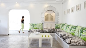 A modern living room with a white sofa, a white coffee table, and a large window. - Crystal Palace (Santorini)
