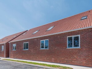 A long brick building with a red-tiled roof and multiple windows.