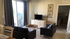 A living room with a TV, sofa, and dining area. - Cane Island (Kissimmee)