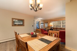 A dining area with a wooden table, chairs, a chandelier, and a framed picture on the wall.