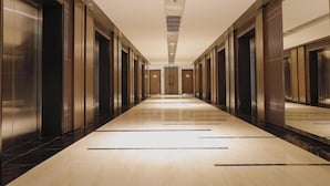 A long, narrow hallway with elevators on both sides and a light-colored floor. - Cala Bayview Muong Thanh (Bac Nha Trang)