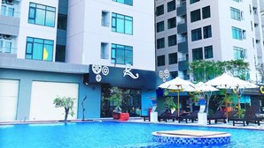 A modern high-rise building with a swimming pool and outdoor seating area. - Cala Bayview Muong Thanh (Bac Nha Trang)