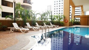 A swimming pool with lounge chairs and palm trees. - A Best Seri Bukit Ceylon Serviced Residence (Kuala Lumpur)