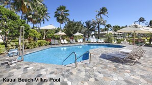 A swimming pool with lounge chairs and umbrellas, surrounded by palm trees and greenery. - Kauai Beach Villas D-9 ... Centrally located ... & Lagoon view (Lihue)