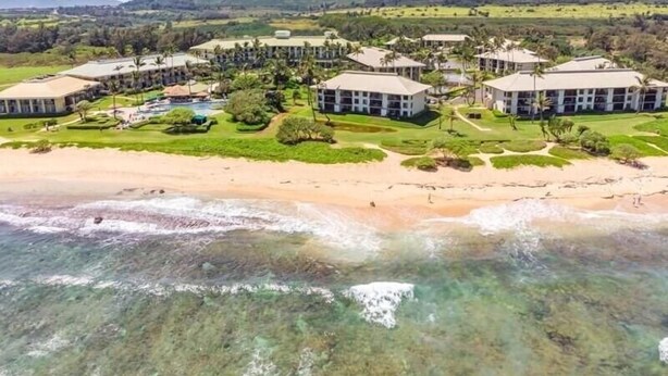 A resort with multiple buildings, a beach, and a mountainous backdrop. - Kauai Beach Villas D-9 ... Centrally located ... & Lagoon view (Lihue)