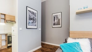 A modern apartment with a kitchen, a living area with a sofa and a blue throw, and two framed photographs on the walls. - Apartamenty Pod Wawelem Wroblewskiego (Kraków)