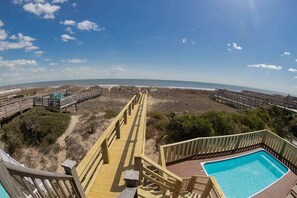 A wooden deck with a pool and a view of the beach. - Pirate`s Booty by Brunswick Vacation Rentals: OIB 5BR Oceanfront Home w/ Pool (Ocean Isle Beach)
