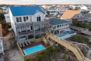 A multi-story beachfront house with a pool, wooden deck, and multiple balconies. - Pirate`s Booty by Brunswick Vacation Rentals: OIB 5BR Oceanfront Home w/ Pool (Ocean Isle Beach)