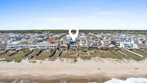 A coastal residential area with houses, a beach, and a pier. - Pirate`s Booty by Brunswick Vacation Rentals: OIB 5BR Oceanfront Home w/ Pool (Ocean Isle Beach)