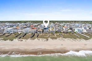 A coastal residential area with houses, a beach, and a pier. - Pirate`s Booty by Brunswick Vacation Rentals: OIB 5BR Oceanfront Home w/ Pool (Ocean Isle Beach)