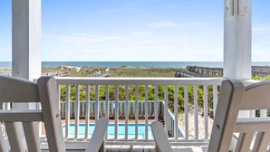 A balcony with a pool, overlooking a beach and a boardwalk. - Pirate`s Booty by Brunswick Vacation Rentals: OIB 5BR Oceanfront Home w/ Pool (Ocean Isle Beach)
