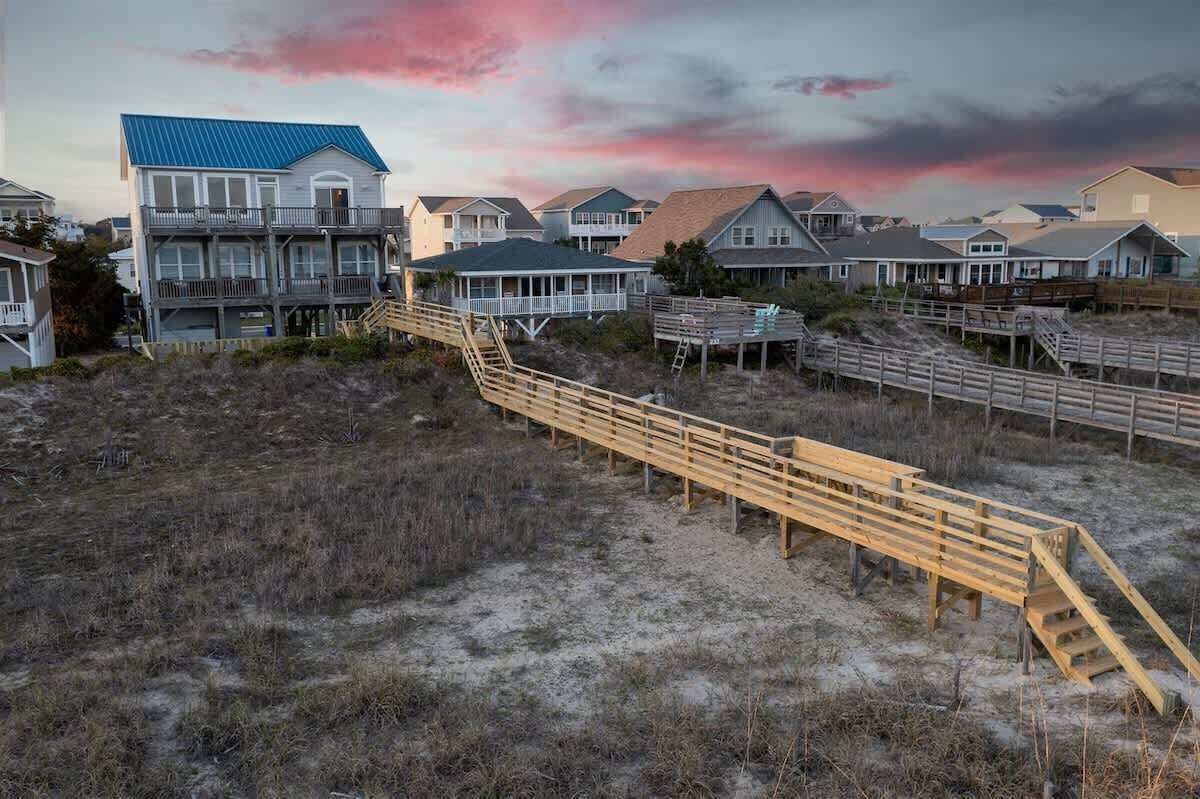 A beachfront property with a wooden boardwalk leading to a building with a blue roof.