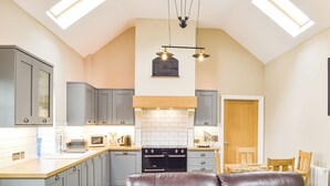 Une cuisine avec des meubles gris, un plan de travail en bois, une cuisinière noire et un canapé en cuir marron.