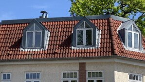 Een gebouw met een rode dakbedekking, meerdere ramen en een bakstenen gedeelte.