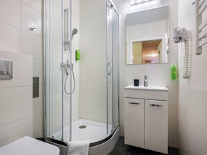 Un baño moderno con ducha de vidrio, lavamanos blanco y espejo sobre el lavamanos.