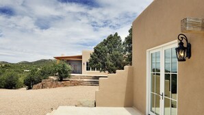 A modern house with a stone staircase leading to a door, surrounded by a gravel driveway and greenery. - 3 Bedroom, 3 Bath Home plus 1 Bedroom, 1 Bath Casita -12 min. to Santa Fe center (Santa Fe)