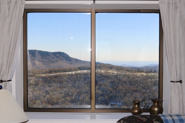 A room with a large window offering a view of a mountainous landscape. - Quaint 5th Floor Condo - Pool and Hot Tub Access! (Sugar Mountain)