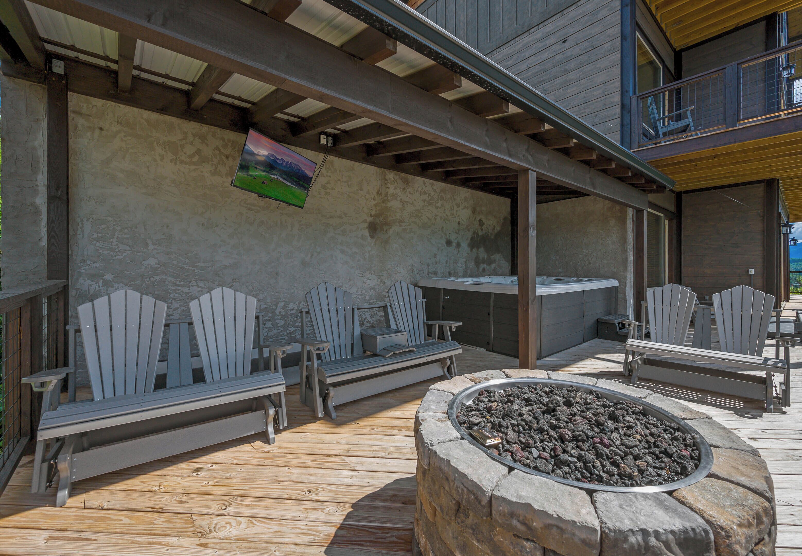 Una terraza al aire libre con sillas Adirondack, un hogar de piedra y vista a un edificio con balcón.