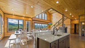 Una cocina amplia con una isla grande, techo de madera y ventanas grandes que ofrecen vistas a la montaña.