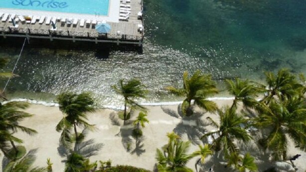 A pool area with a 'Sunrise' sign, a wooden deck, and palm trees. - Penthouse Sun Rise San Andrés (San Andrés)