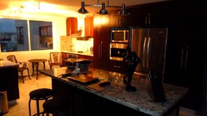 A modern kitchen with a central island, stainless steel appliances, and wooden cabinets. - Penthouse Sun Rise San Andrés (San Andrés)