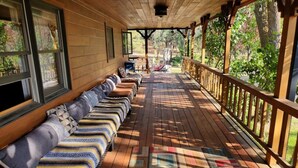 Une véranda couverte avec des bancs en bois et un tapis à motifs.