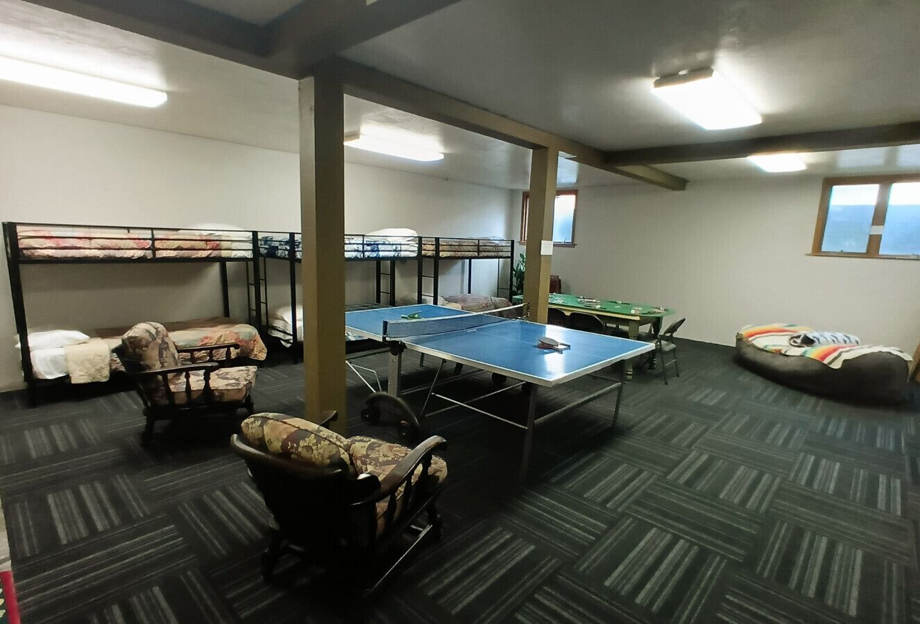 A room with bunk beds, a ping pong table, and a bean bag chair.