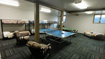 A room with bunk beds, a ping pong table, and a bean bag chair.