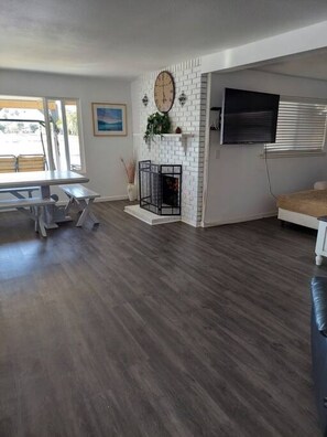 A spacious living room with a fireplace, a dining table, and a TV mounted on the wall.