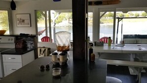 Een keuken met een groot eiland, een eethoek met een bank, en uitzicht op het water.