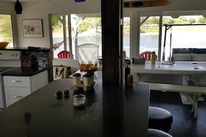 A kitchen with a large island, a dining area with a bench, and a view of the water outside. - Charming Riverfront Escape with Private Dock on the Colorado (Mohave Valley)