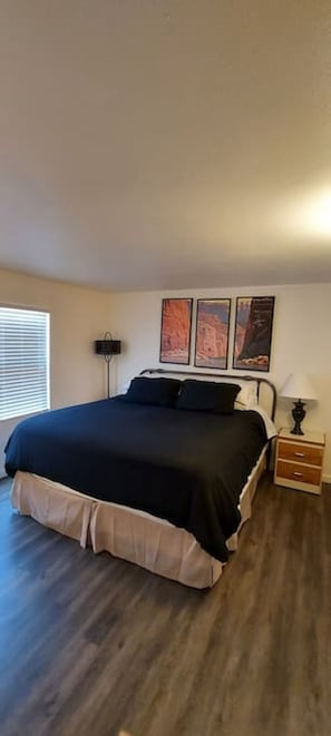 A bedroom with a bed, a nightstand, a lamp, and three framed pictures on the wall.