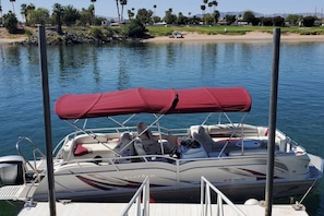 A motorboat docked at a marina with a red canopy, equipped with seating and a steering wheel.
