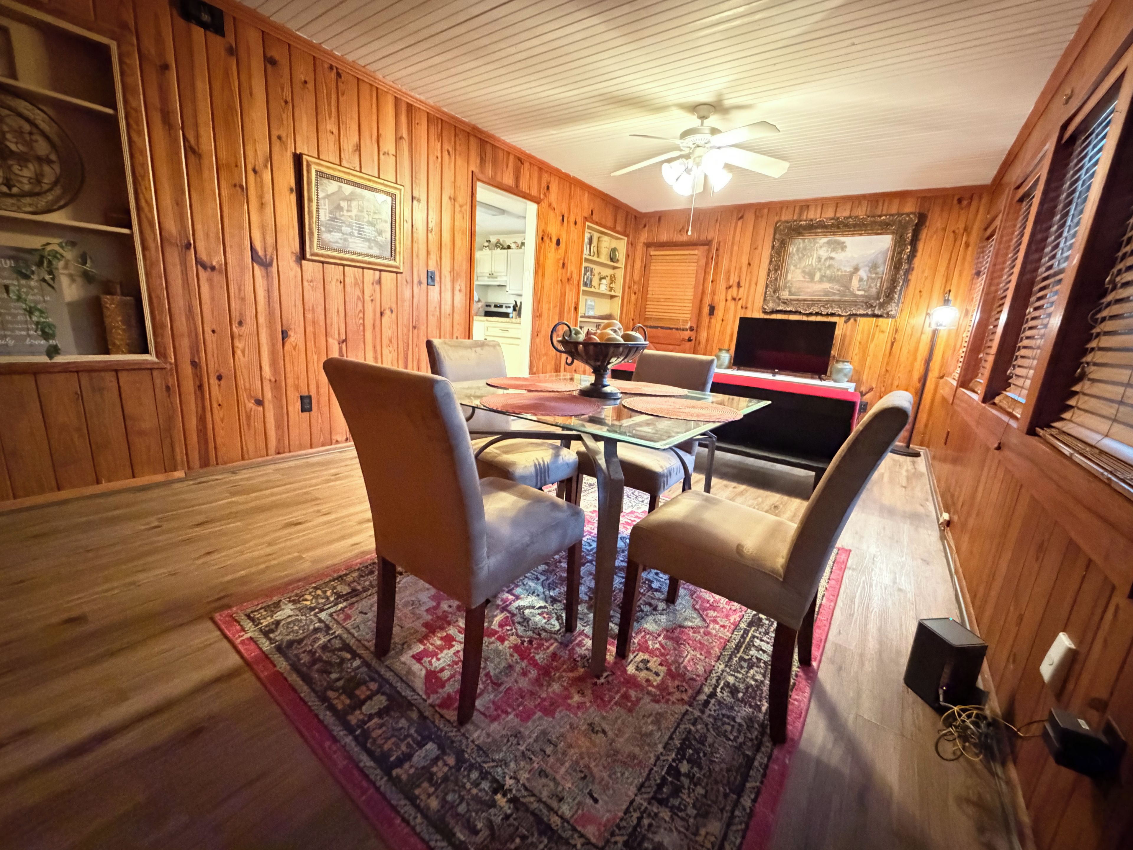 A dining area with a wooden interior, a ceiling fan, and a dining table with chairs.