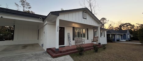Ein zweistöckiges Haus mit einer Veranda, einem Briefkasten und der Hausnummer 305 an der Wand.